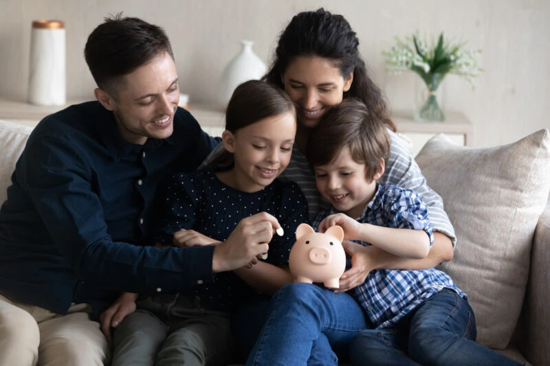 family sitting on a couch holding a piggy bank